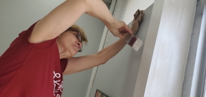 Myra Poplin, co-owner of Speckled Paw Coffee, paints trim work at the shop&#039;s new location in Rockingham, set to open Friday.