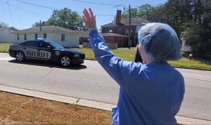 An employee of FirstHealth Moore Regional Hospital-Richmond waves as a passing deputy offers thanks during a parade in April.