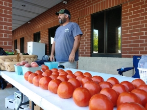 Josh Blake, of T and K Farms in Exway, stands behind a row of tomatoes Tuesday afternoon at the Richmond County Farmers&#039; Market.