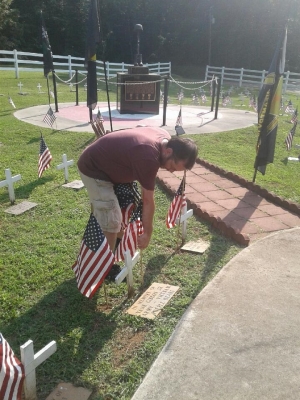 Donny Sweatt, a member of the VFW Post 4203 Auxiliary, places flags at Veterans Memorial Park on Thursday in preparation for Saturday&#039;s service. 