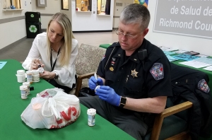 Health Educator Laine Floyd and Lt. N.L. Forester mark out the names on pill bottles during a medication take-back event Wednesday at the Richmond County Health Department.