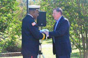 Recently retired Hamlet Fire Chief Calvin White receives a commemorative fire service coin from Insurance Commissioner Mike Causey during a memorial service for the 30th anniversary of the Imperial Foods fire.
