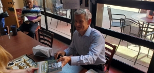 Sam McGee hands over a signed copy of his debut novel &quot;Cartledge Creek&quot; during a book signing Thursday afternoon at Pattan&#039;s Downtown Grille.