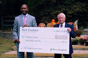 Tyrone Tyler, left, regional senior vice president of the State Employees Credit Union, hands a $1 million check to Harold Pearson, executive director of Samaritan Colony, to aid in the construction of the SECU Women&#039;s Recovery Center.