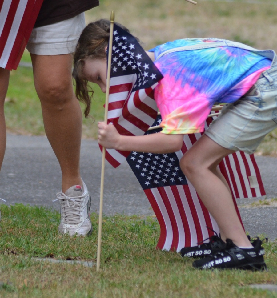 Evie Hutchinson places a U.S. flag at the grave of a Richmond County veteran Tuesday at Eastside Cemetery. See more photos on the RO&#039;s Facebook page.