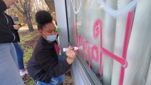 Tenth-grade Beta Club member Honesty Horne writes &quot;Happy Holidays&quot; backwards so it can be read from the inside of a window at PruittHealth Rockingham.