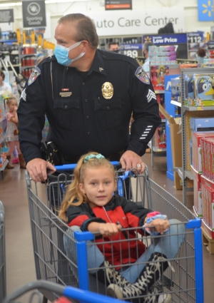 Sgt. Lee Bailey pushes 10-year-old Kendal Rushing through Walmart during the annual Shop with a Cop program. See more photos at the bottom of this story.